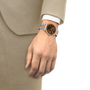 Hand wearing a watch with a beige suit on a white background