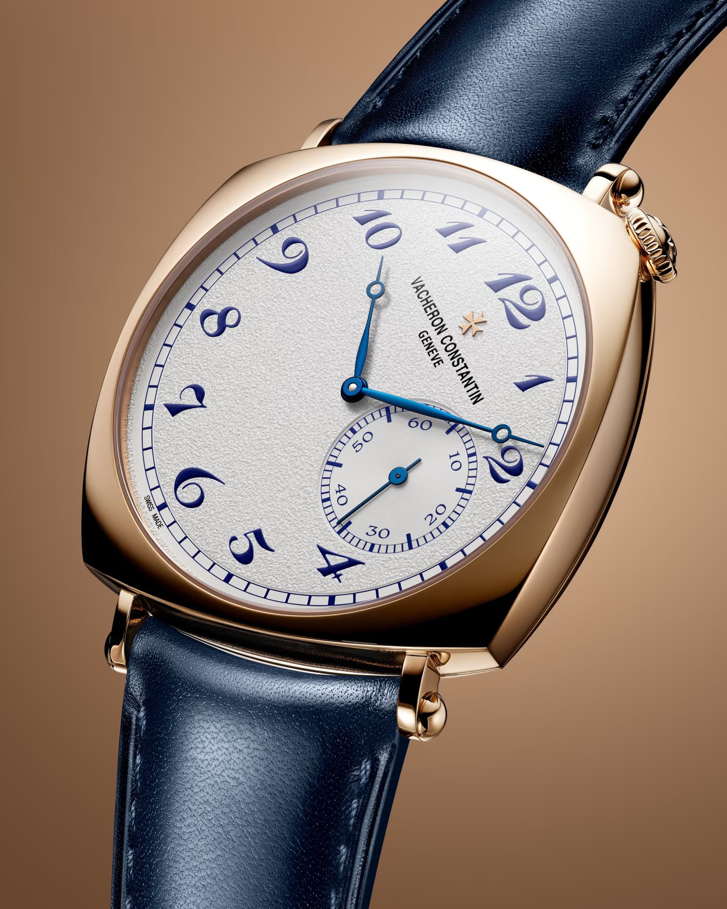 Gold-tone watch with white dial, blue Arabic numerals, blue hands, and dark blue leather strap.