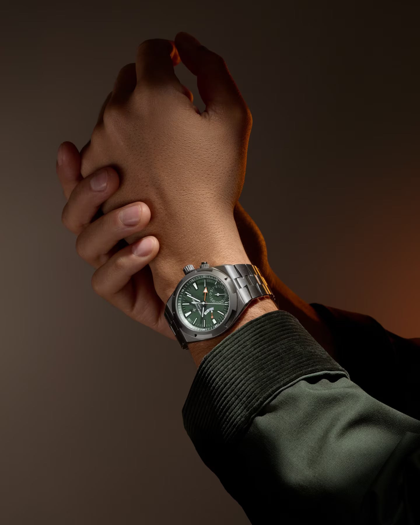 Stainless steel watch with green dial and chronograph subdials worn on wrist.