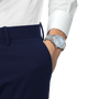 Silver watch on a wrist with a white shirt and navy pants against a white background