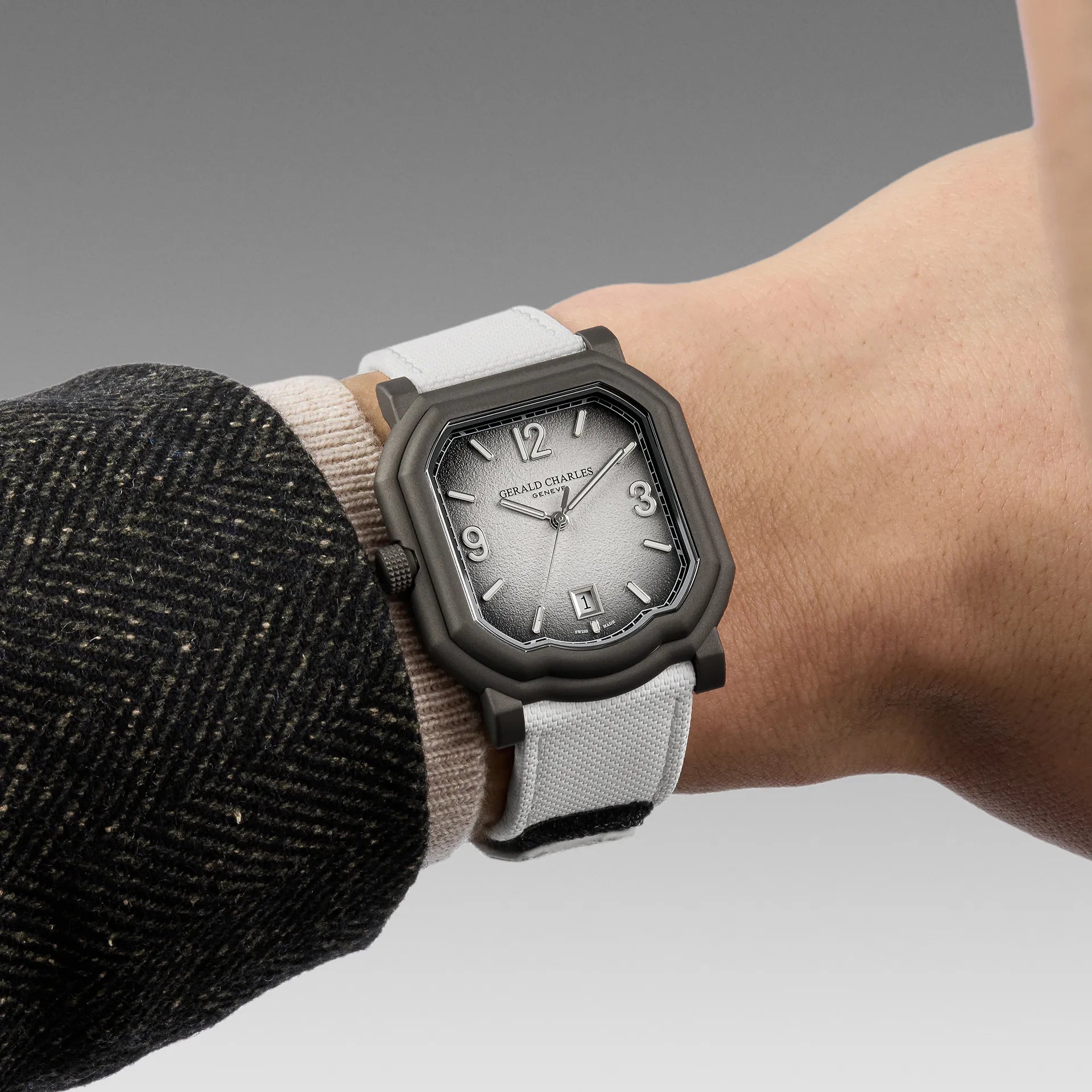 Watch with a gray strap on a wrist, against a neutral background