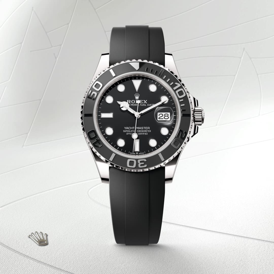 A black Rolex Yacht-Master watch with a rubber strap displayed on a light textured background.
