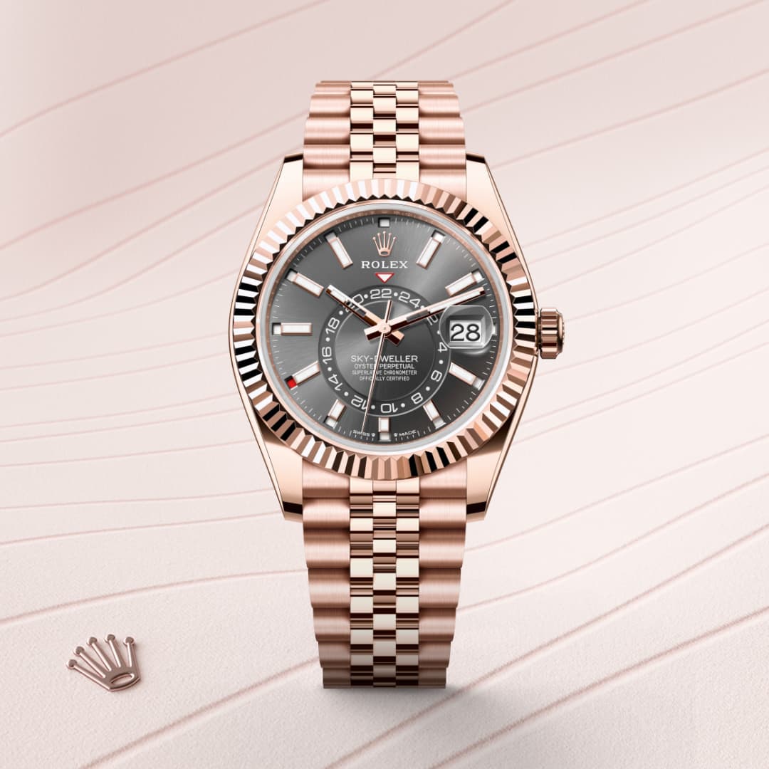 A rose gold Rolex Sky-Dweller watch with a dark dial is displayed on a light, wavy-patterned background.