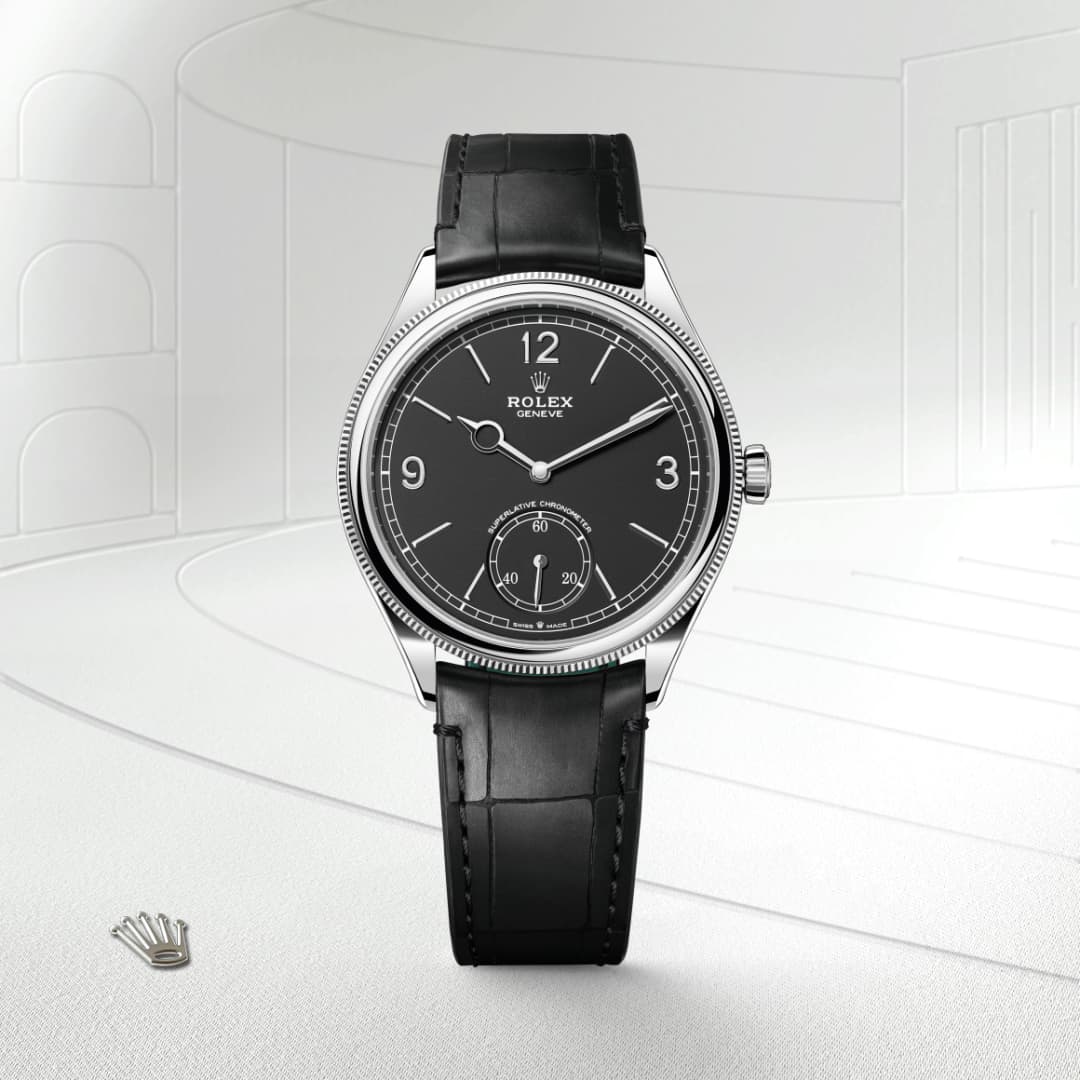 A luxury Rolex wristwatch with a black leather strap and a black dial on a light, minimal background.