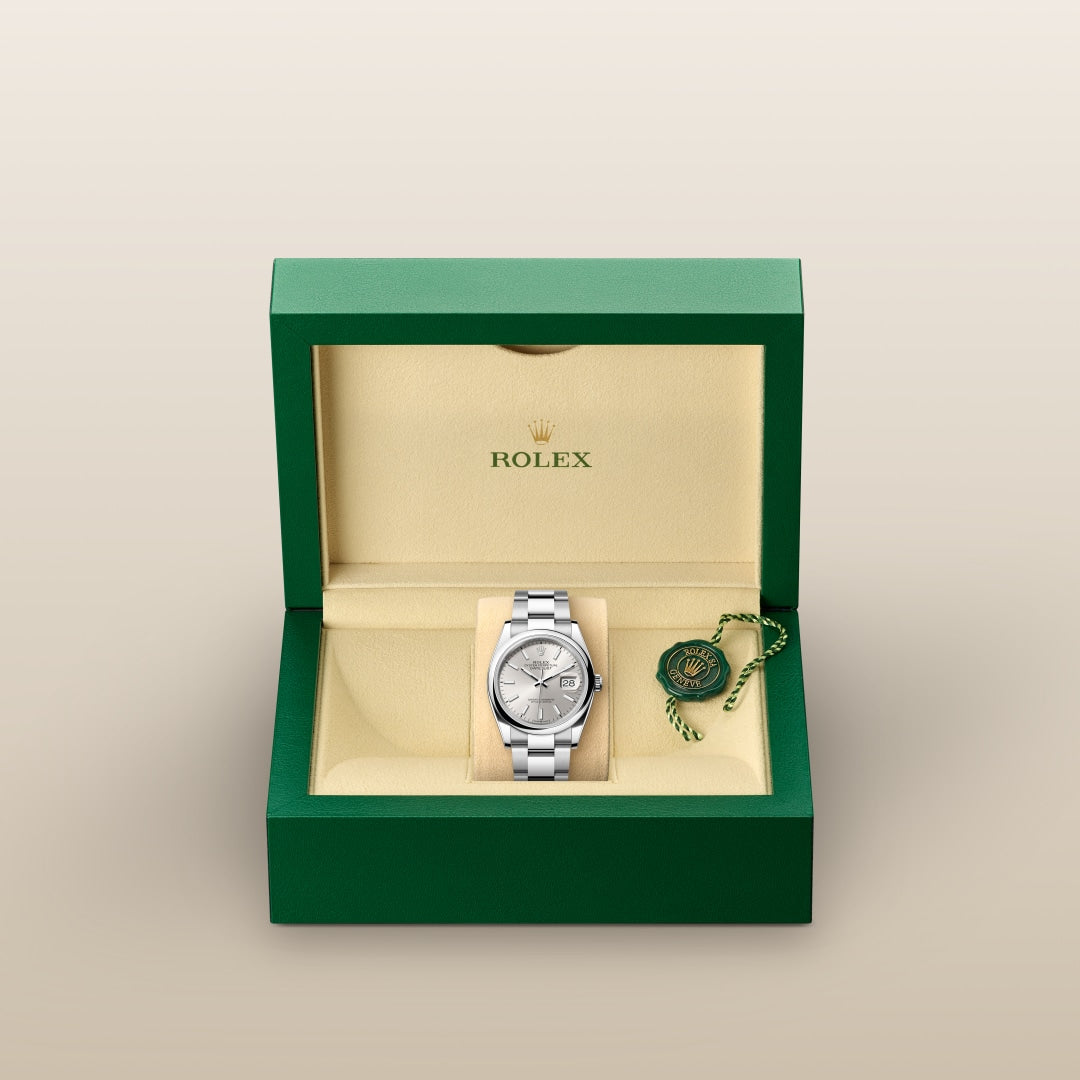 A silver Rolex watch in a green and beige box with a Rolex tag beside it.