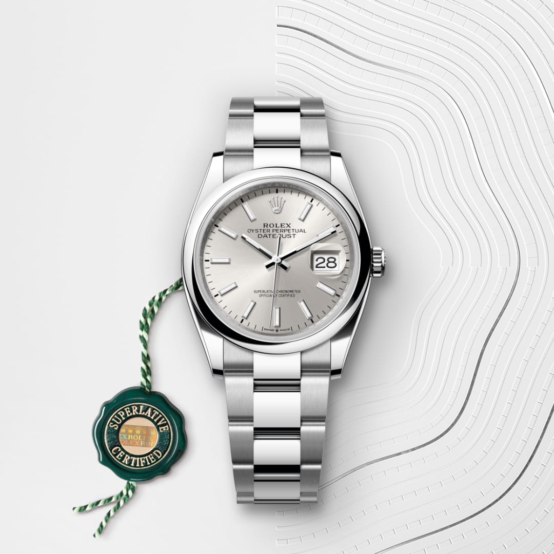 Silver Rolex Datejust watch with a metal band, shown alongside a green Superlative Certified seal.