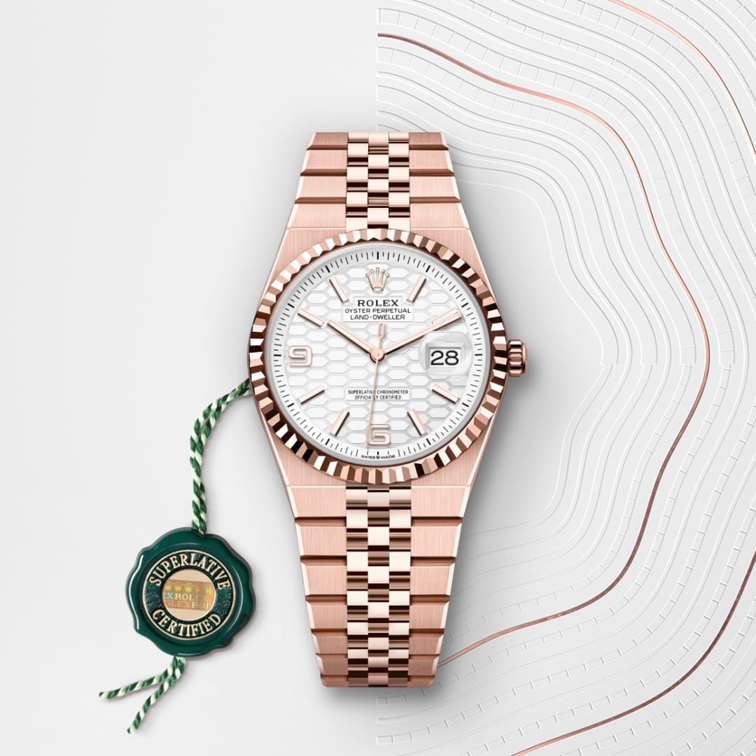 A rose gold Rolex watch with a white dial and date display, next to a green Superlative Certified tag.