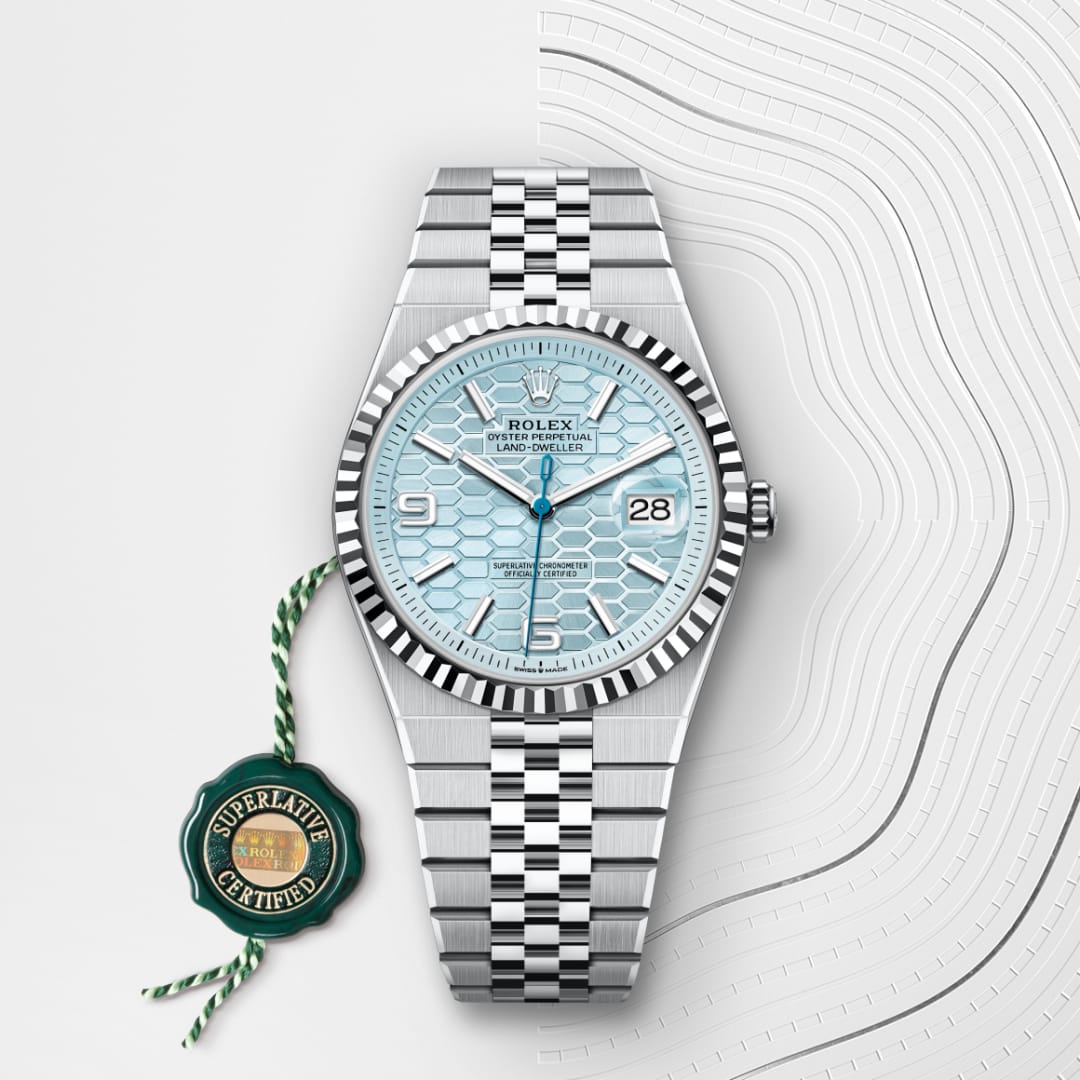 Silver Rolex wristwatch with light blue dial and date display, next to a green Superlative Certified tag.
