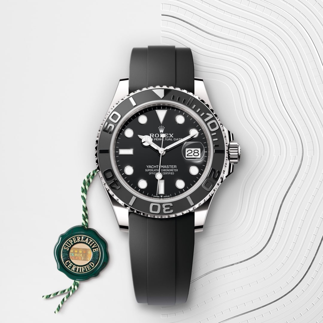 A Rolex Yacht-Master watch with a black strap and Superlative Certified tag on a white geometric background.