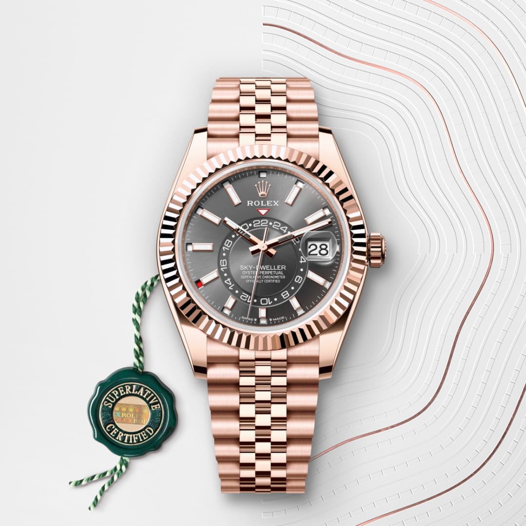 A rose gold Rolex Sky-Dweller watch with a dark dial and date display, next to a green Superlative Certified tag.