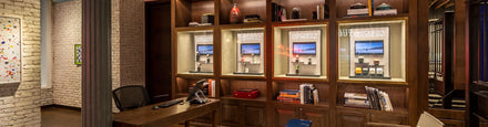 A stylish office with wood shelves displaying Watches of Switzerland signs and empty watch stands.