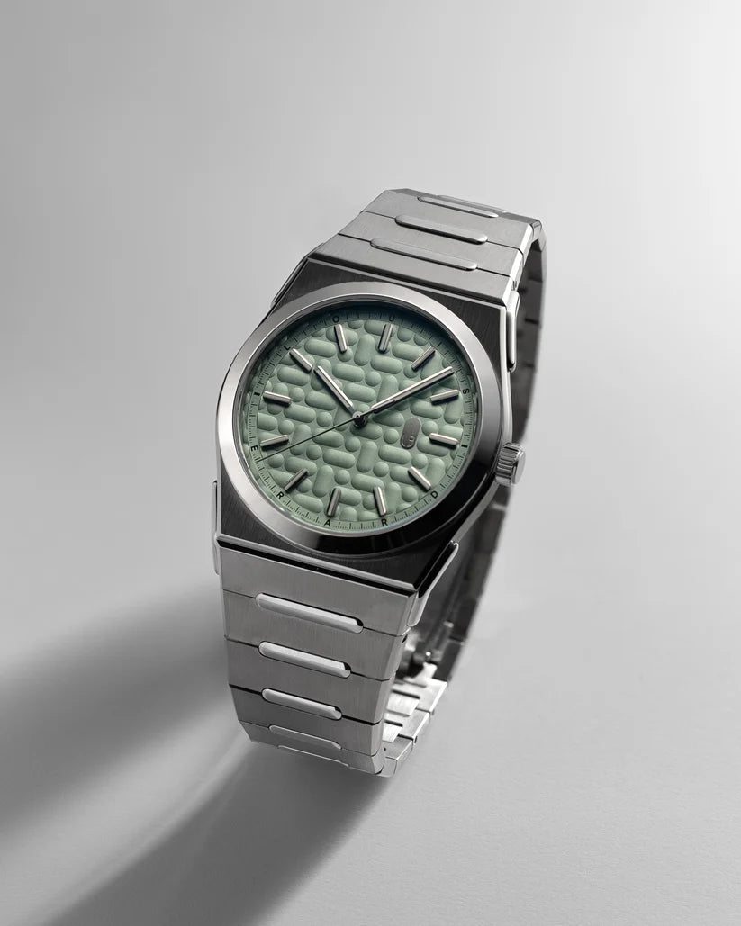 Silver watch with a green textured face on a light gray background
