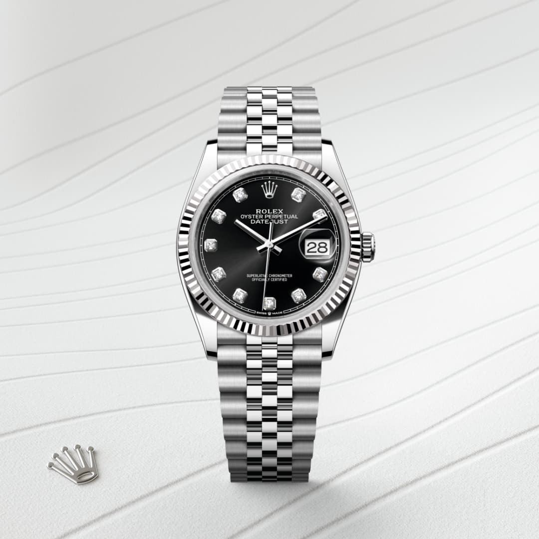 A silver Rolex watch with a black dial and diamond hour markers on a textured white surface.