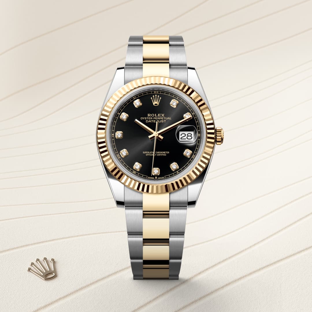 A Rolex Datejust watch with a black dial, gold and silver bracelet, and diamond hour markers on a beige background.