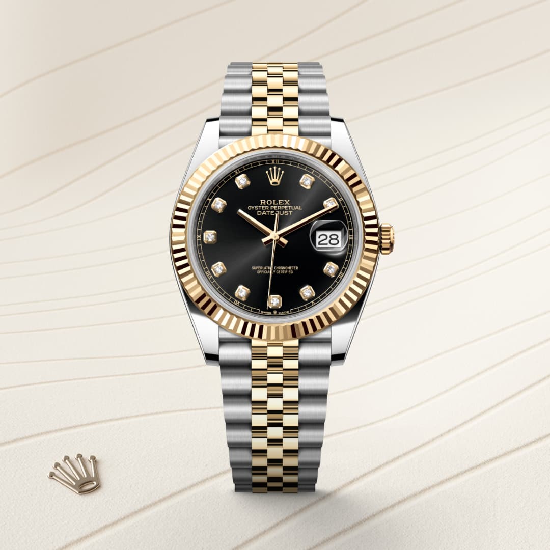 A two-tone Rolex watch with a black dial, date display, and diamond hour markers on a light textured background.