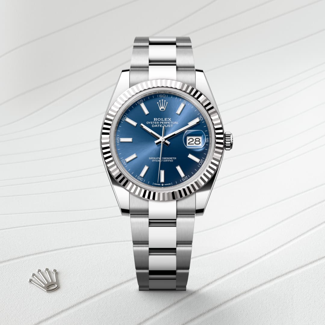 A stainless steel Rolex watch with a blue dial and date display, shown on a textured white background.
