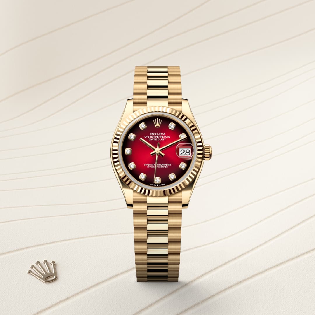 A gold Rolex watch with a red dial and diamond markers, displayed on a cream textured surface.
