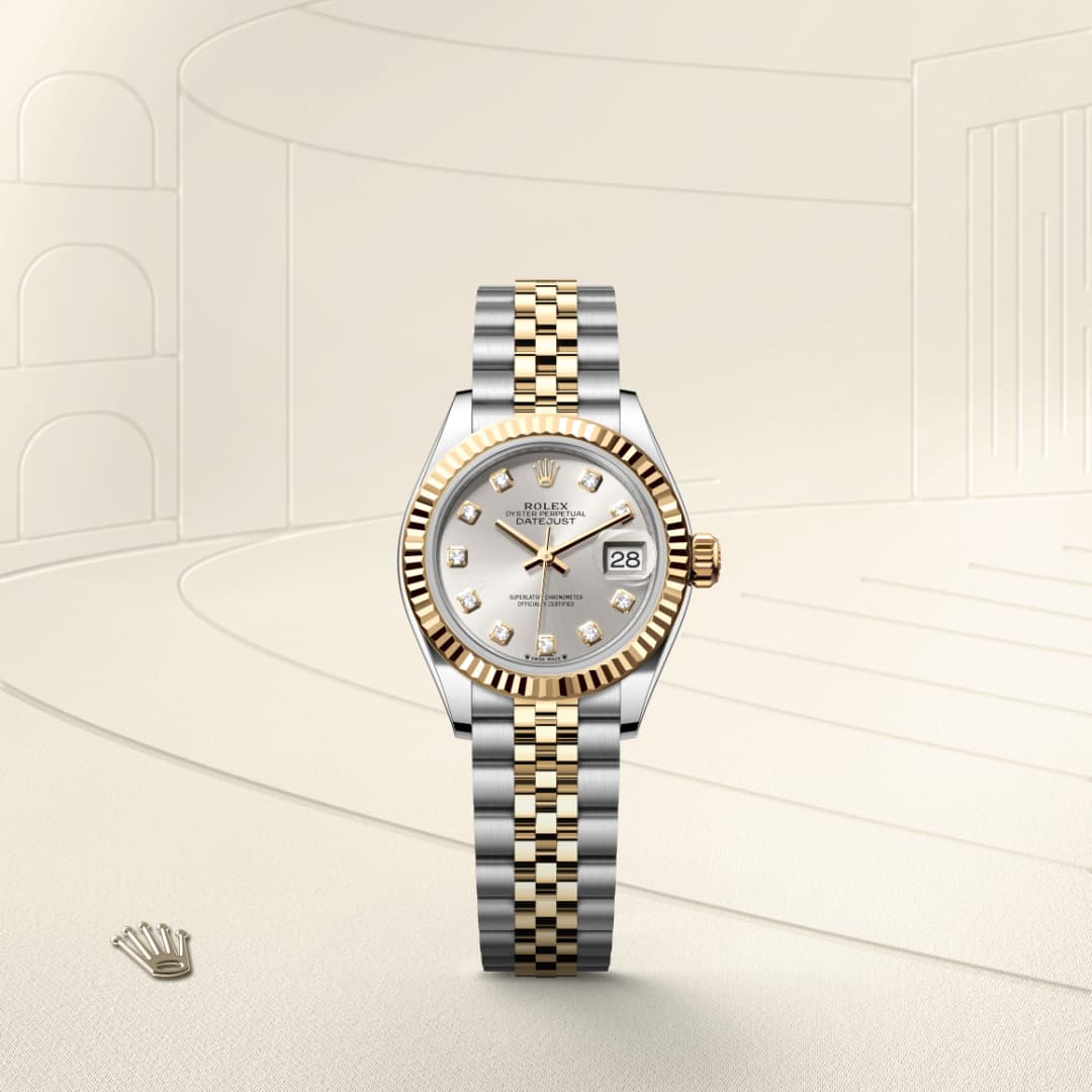 A Rolex watch with a gold and silver band, diamond hour markers, and a date display on a light background.