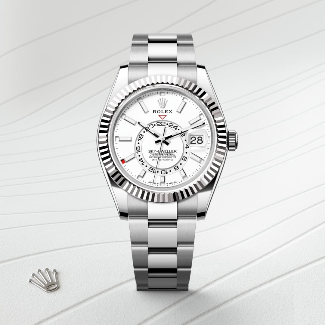 A silver Rolex Sky-Dweller watch with a white dial, metal bracelet, and a small crown logo beside it.