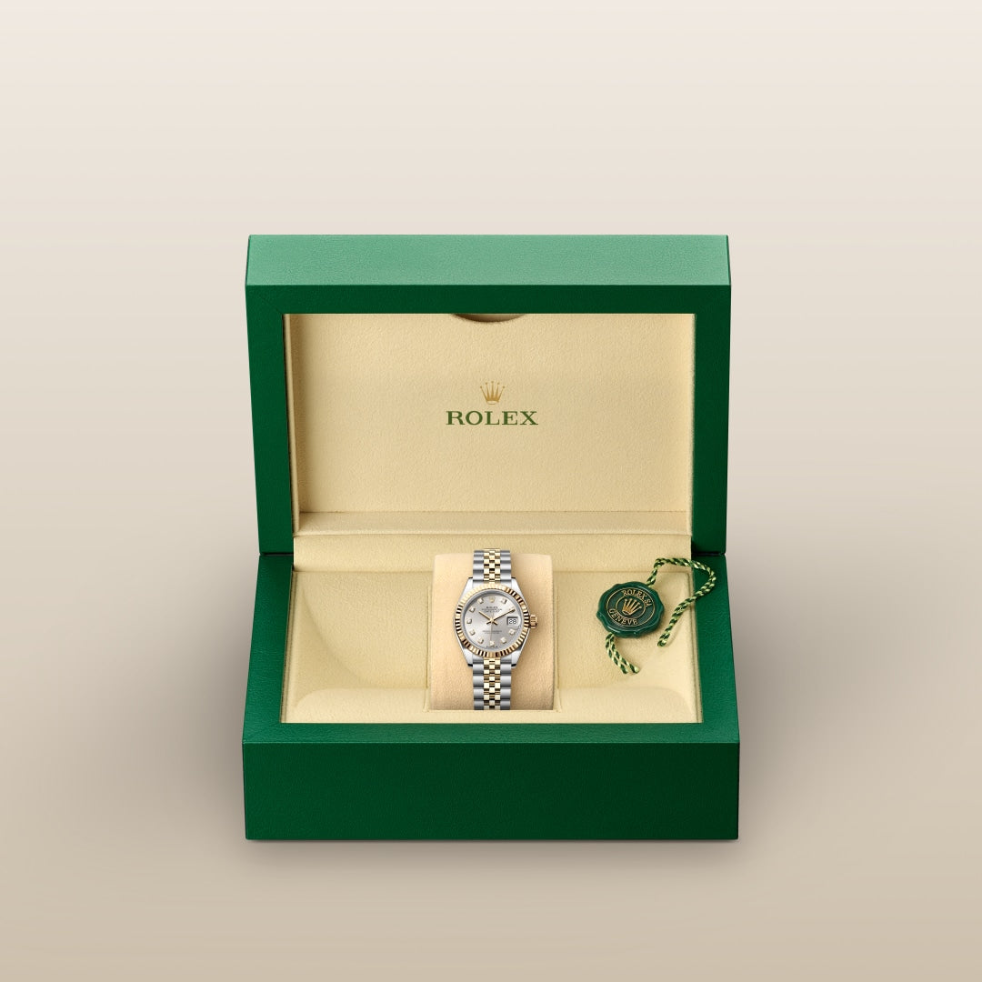 A Rolex wristwatch in a green and beige box with a green tag beside it on the right.