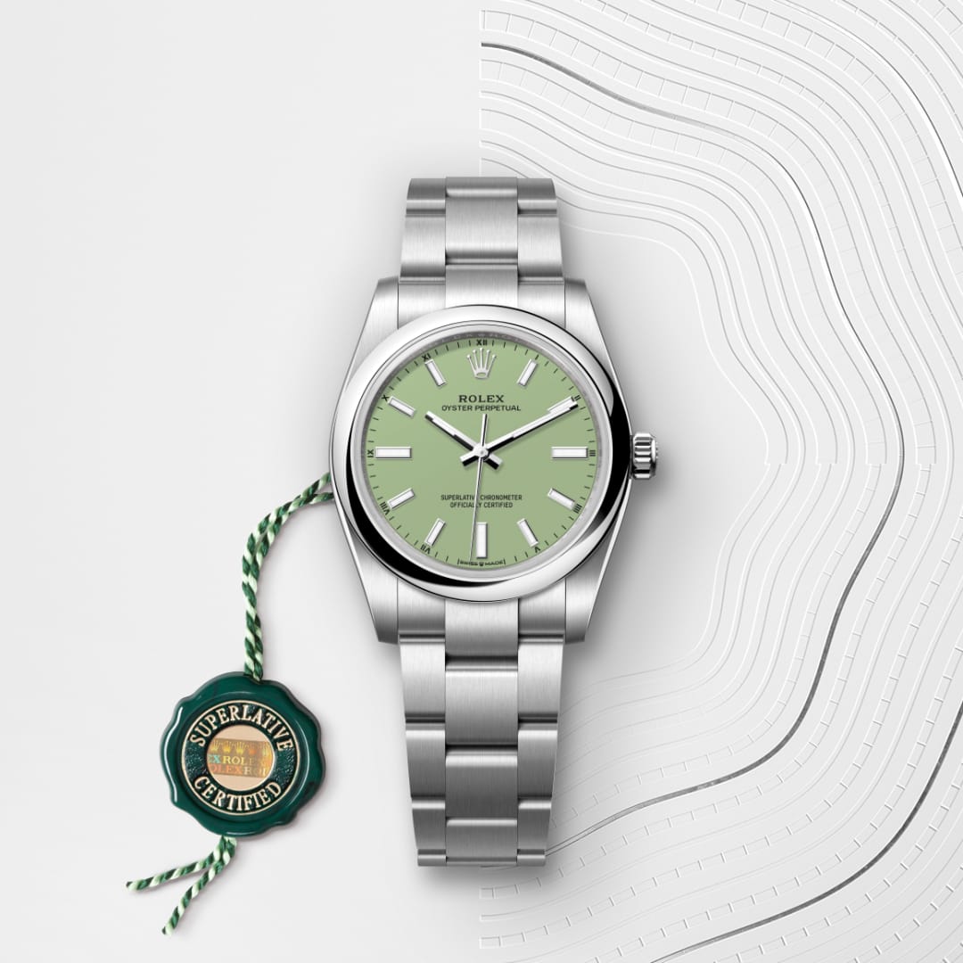 A silver Rolex watch with a green face and a Superlative Certified tag on a white textured background.