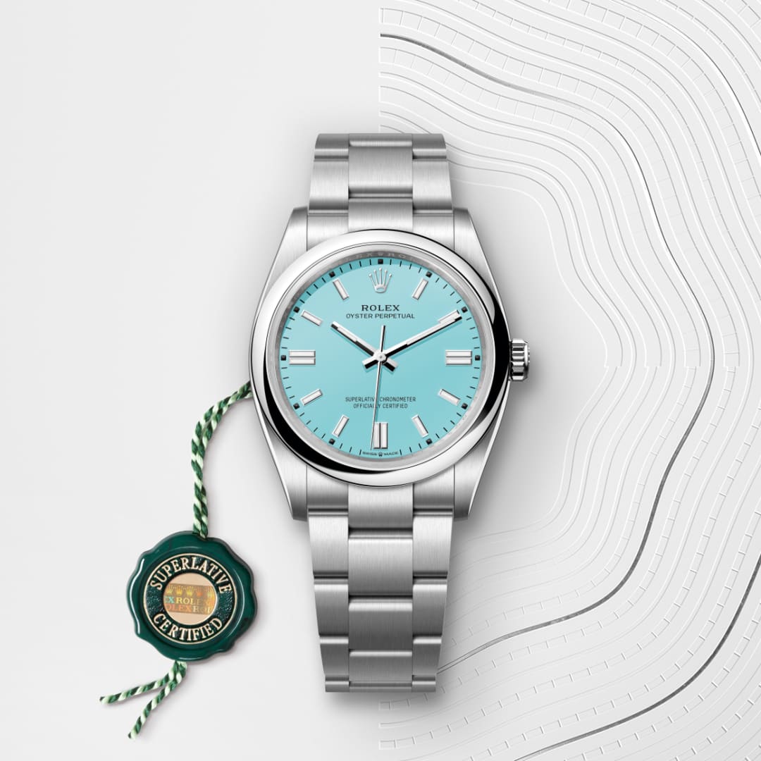 A silver Rolex watch with a turquoise face and a green Superlative Certified tag on a white patterned background.