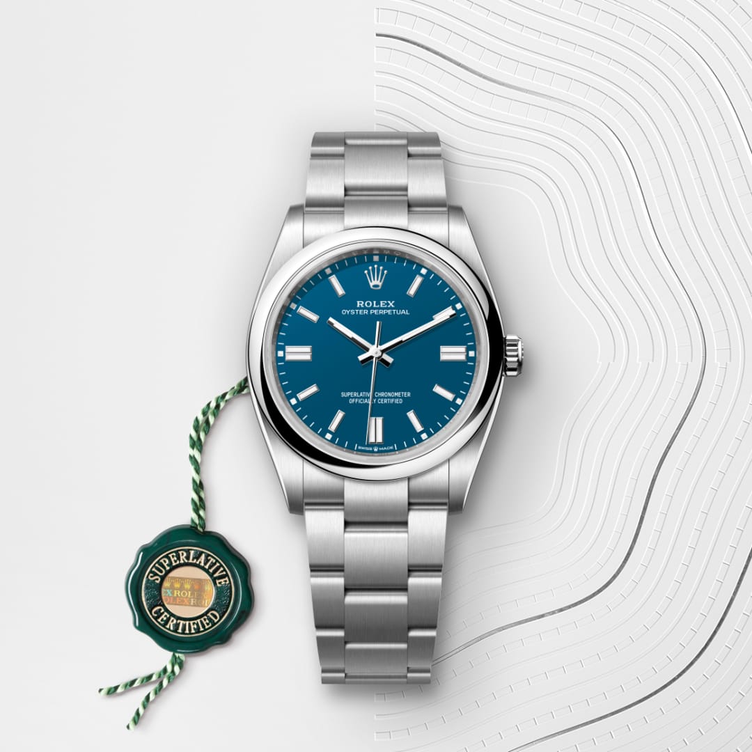 A silver Rolex watch with a blue face and a green Superlative Certified tag on a white textured background.