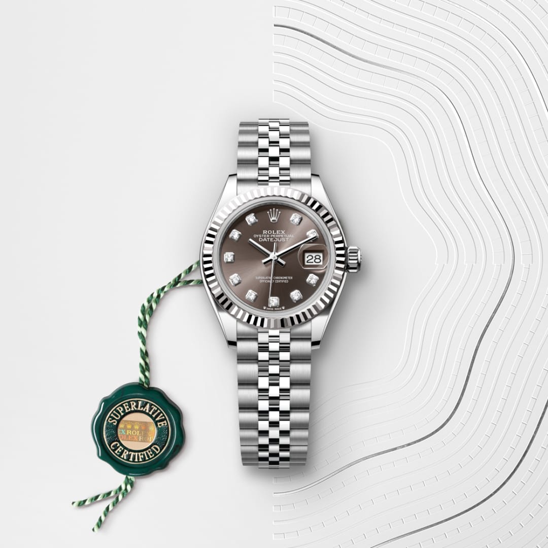 Silver Rolex watch with a dark face, diamond hour markers, and a Superlative Certified green tag attached.