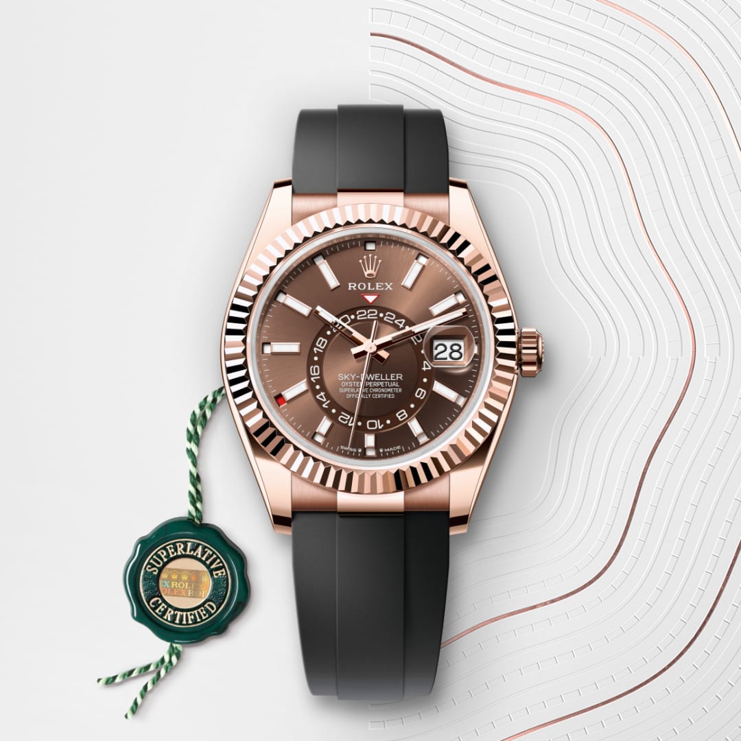 A rose gold Rolex Sky-Dweller watch with a black strap, displayed beside a Superlative Certified tag.