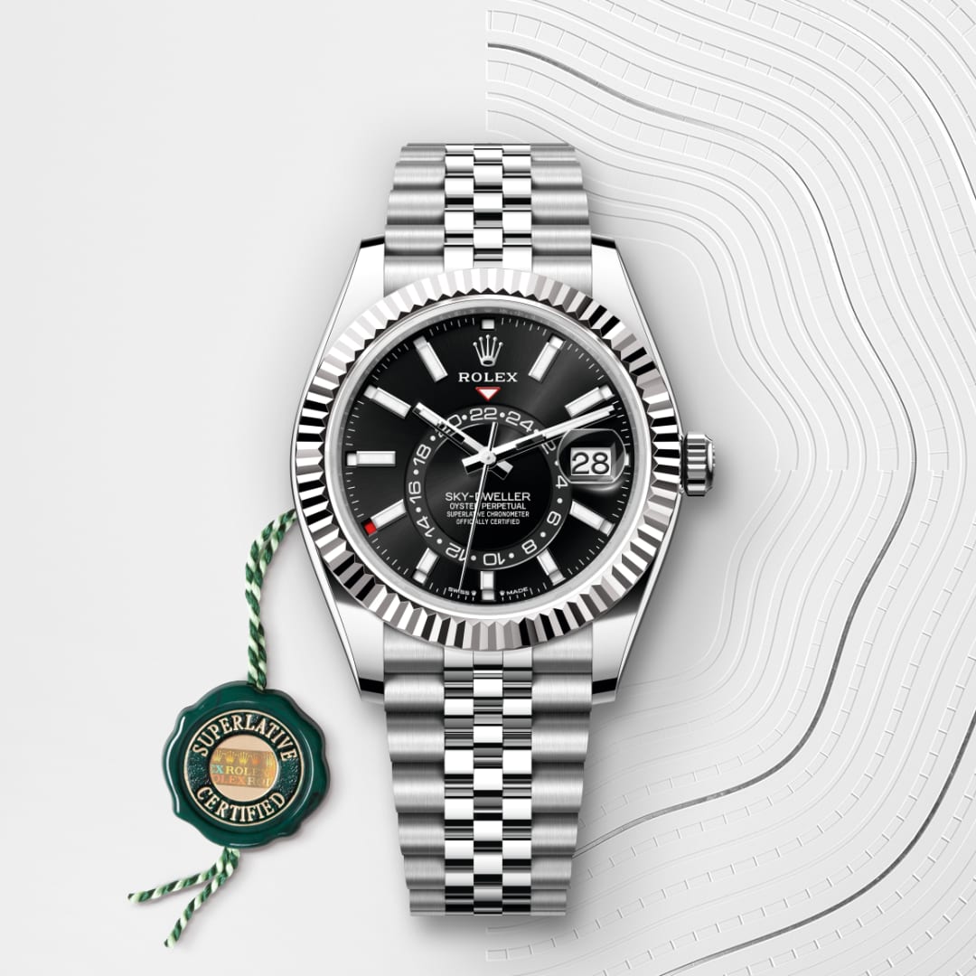 A Rolex Sky-Dweller watch with a black dial and silver bracelet, next to a green “Superlative Certified” tag.