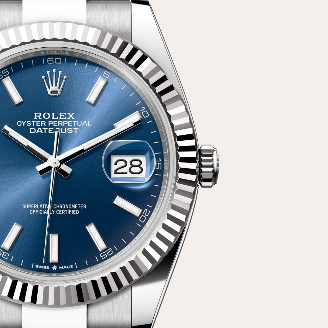 Close-up of a Rolex Datejust watch with a blue dial, silver hands, and date window showing the number 28.