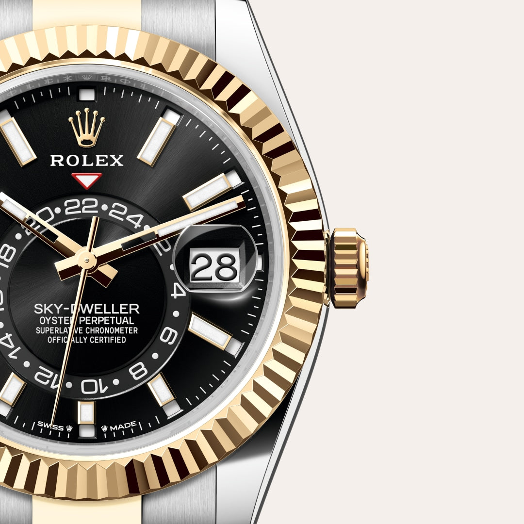 Close-up of a Rolex Sky-Dweller watch with a black dial, gold bezel, and date display showing the 28th.