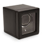 Black leather watch winder with single circular watch holder, transparent front window, and solid top cover.