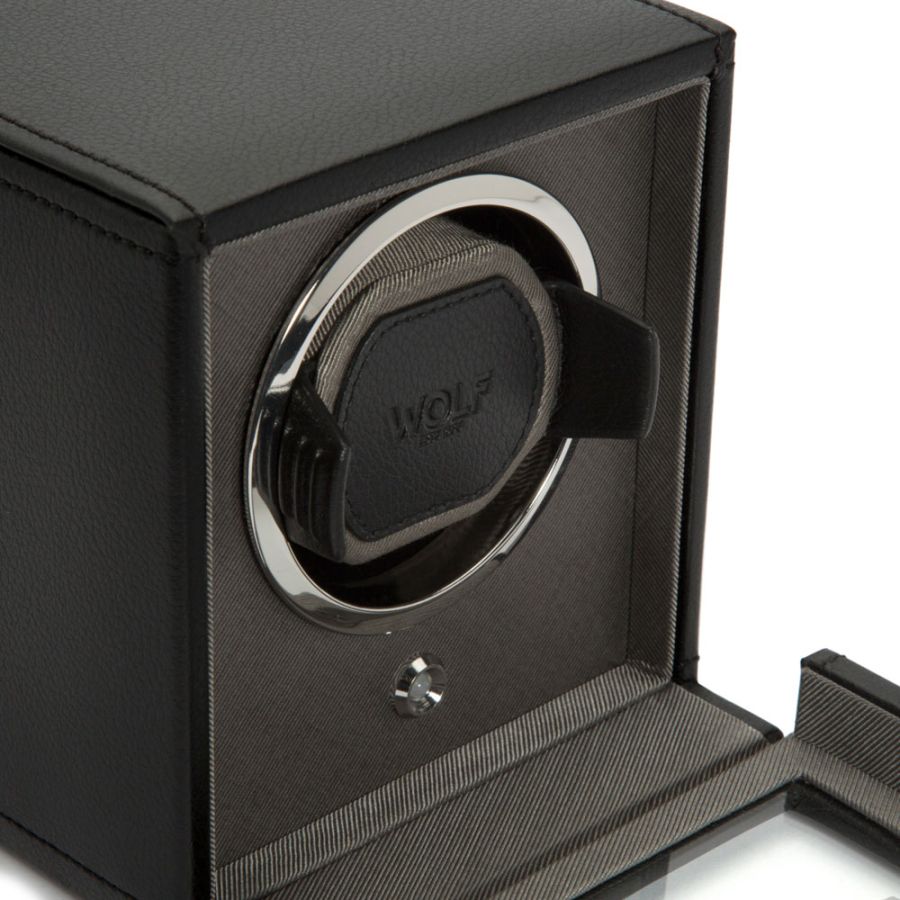 Black watch winder with single rotating cushioned cradle, silver-tone ring, and protective cover, front view.