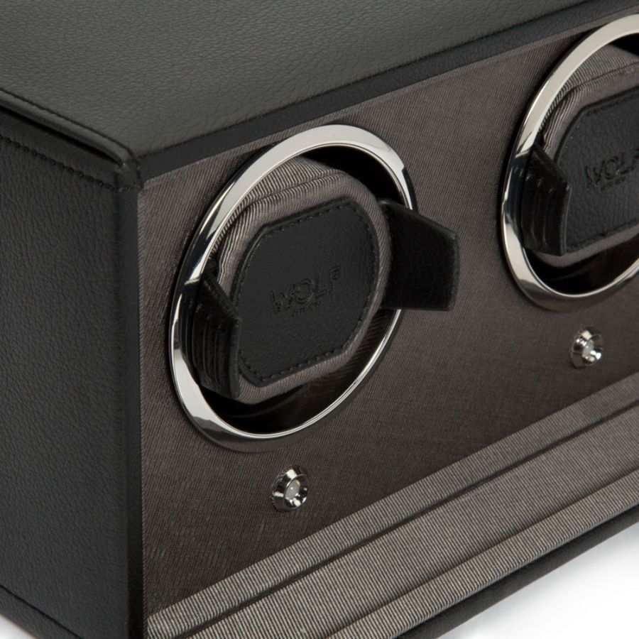 Black watch winder with two circular chrome-rimmed compartments and control buttons on textured front panel.