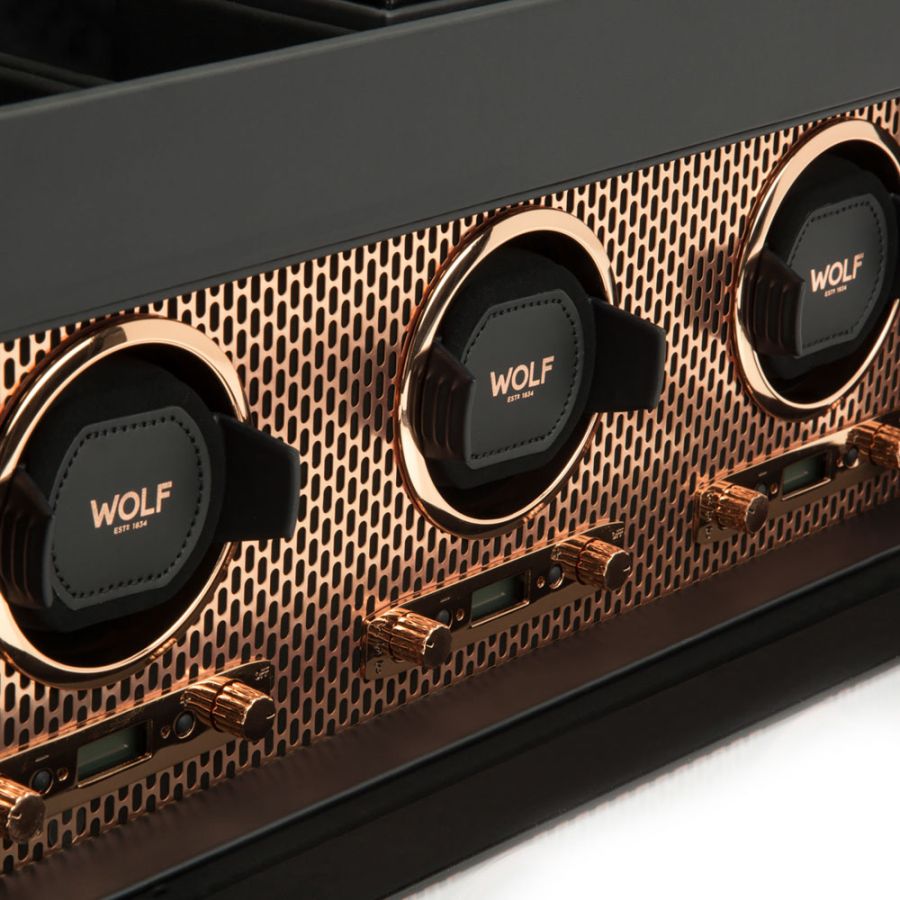Three circular watch winders with gold trim and black leather cushions on a perforated gold and black case.