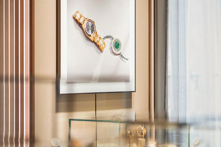 Framed photo of luxury watches hangs above a display case with jewelry in a store.