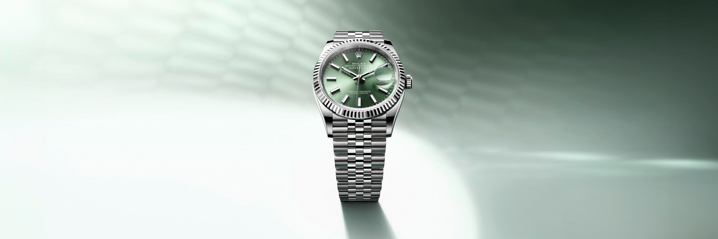 Silver wristwatch with a green face on a metallic band, set against a green gradient background.