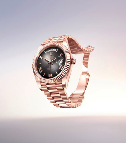 Rose gold luxury wristwatch with a black dial, Roman numerals, and a date display, floating on a light background.