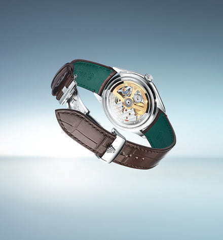 A luxury wristwatch with a brown leather strap, showing its exposed mechanical movement and green inner lining.