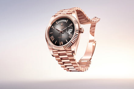 A rose gold luxury wristwatch with a black dial and date display, set against a light gradient background.
