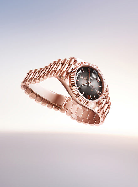 A rose gold wristwatch with a black dial and Roman numerals, displayed against a light gradient background.