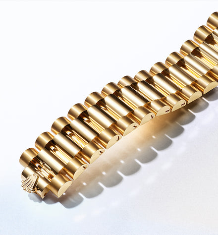 Close-up of a gold link bracelet with a polished, shiny finish on a light background.