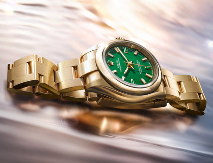 Gold watch with a green face on a blurred background