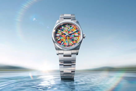 Silver watch with a colorful face on a blue water background