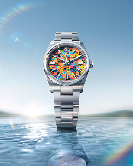 Silver watch with a colorful face on a reflective water surface with a blue sky background