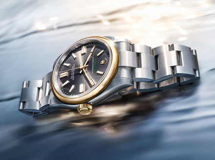 Luxury watch with silver and gold band on a reflective surface
