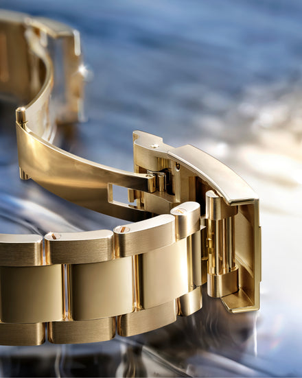 Gold watch bracelet on a reflective surface