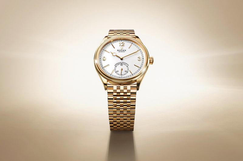 A gold Rolex wristwatch with a white dial displayed on a light beige background.