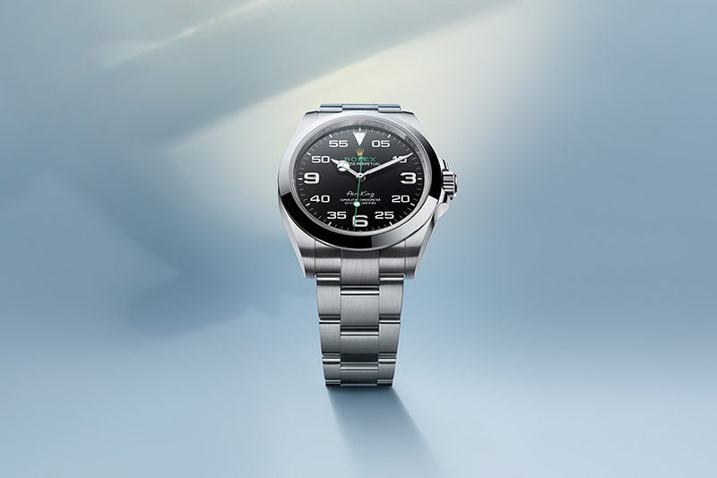 A silver wristwatch with a black dial and white numerals on a light blue background.